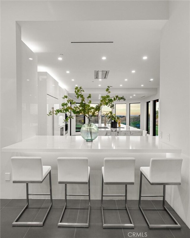 kitchen featuring a peninsula, a kitchen bar, visible vents, modern cabinets, and recessed lighting