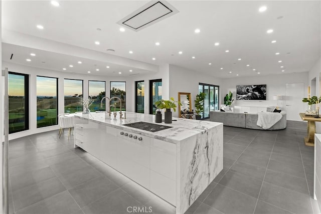kitchen with gas stovetop, white cabinetry, modern cabinets, a large island with sink, and recessed lighting