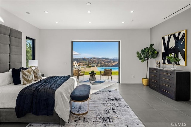 bedroom featuring access to exterior, a water view, and light tile patterned floors