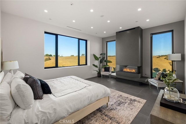bedroom featuring multiple windows, recessed lighting, and a warm lit fireplace