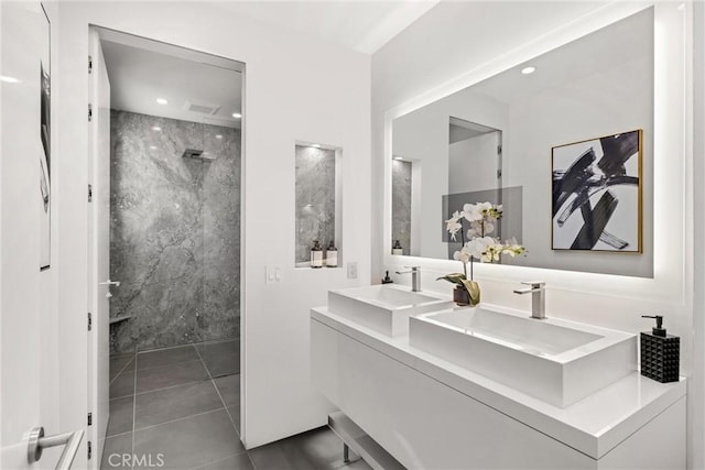 bathroom with double vanity, a marble finish shower, tile walls, and a sink
