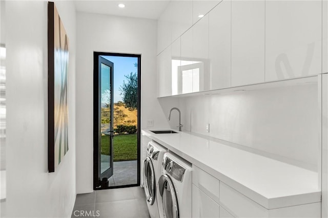 laundry area with washing machine and clothes dryer, sink, light tile patterned flooring, and cabinets