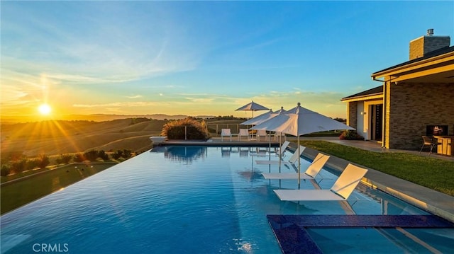 pool at dusk featuring a patio area and an outdoor pool