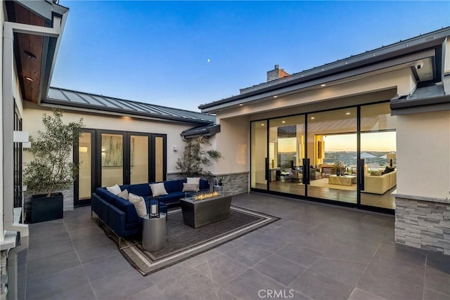 patio terrace at dusk with an outdoor living space with a fire pit