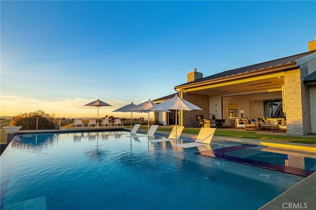 pool at dusk featuring a patio