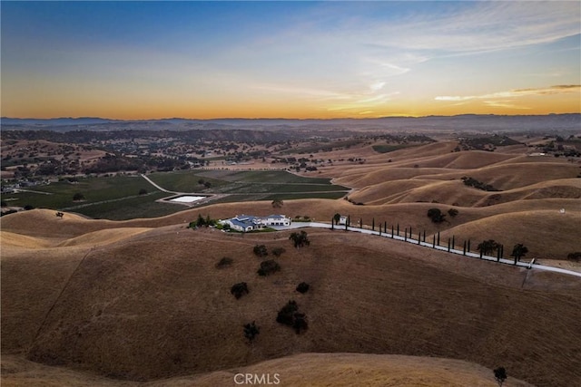 aerial view at dusk with a mountain view and a rural view