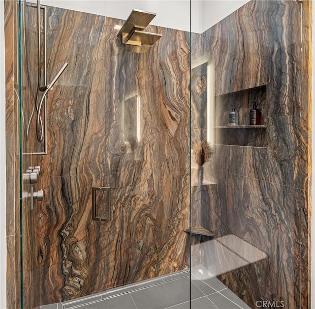 bathroom with a marble finish shower and tile patterned flooring