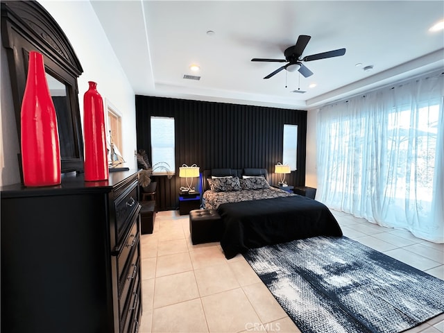 tiled bedroom featuring a raised ceiling and ceiling fan