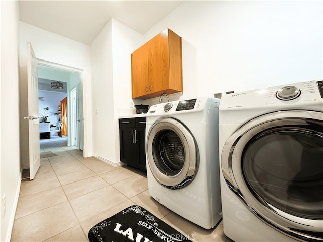 laundry room featuring washer and dryer, cabinets, and light tile patterned floors