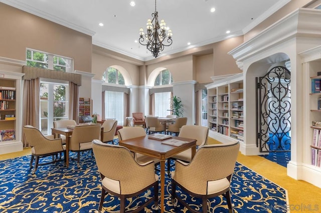 carpeted dining room featuring crown molding, a notable chandelier, a towering ceiling, and decorative columns