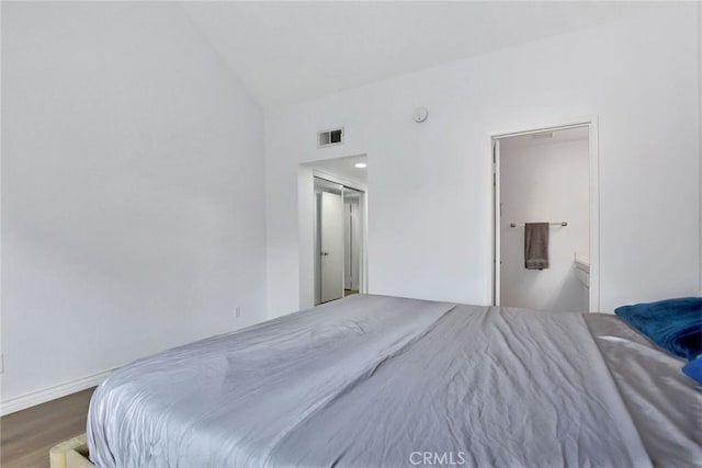 bedroom with visible vents, baseboards, wood finished floors, and vaulted ceiling