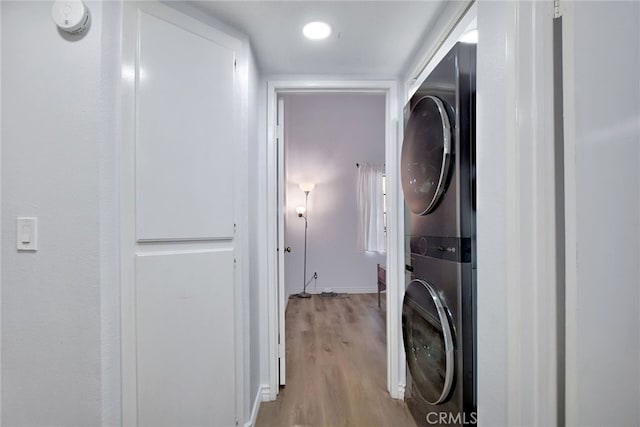 washroom featuring stacked washer / drying machine and light hardwood / wood-style flooring