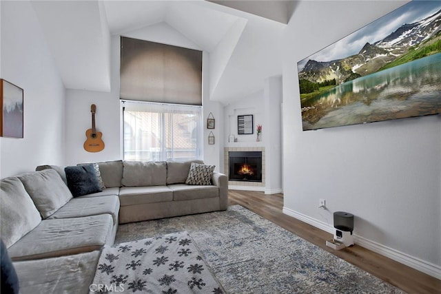 living room with a tile fireplace, dark wood-type flooring, and high vaulted ceiling