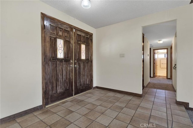 tiled entryway with a wealth of natural light and a textured ceiling