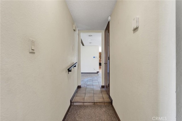 hall with light tile patterned floors and a textured ceiling