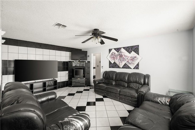 living room featuring ceiling fan, light tile patterned flooring, and a textured ceiling