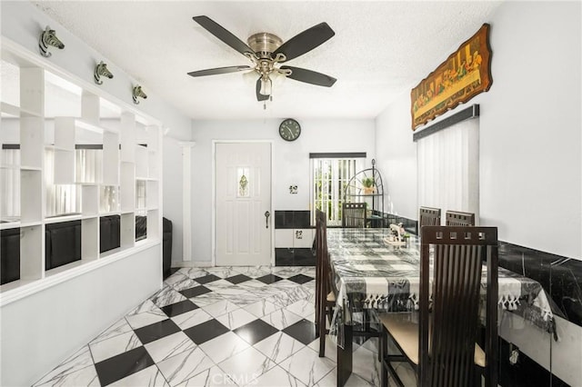 dining area with ceiling fan and a textured ceiling