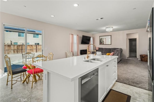 kitchen with light colored carpet, sink, a center island with sink, dishwasher, and white cabinetry