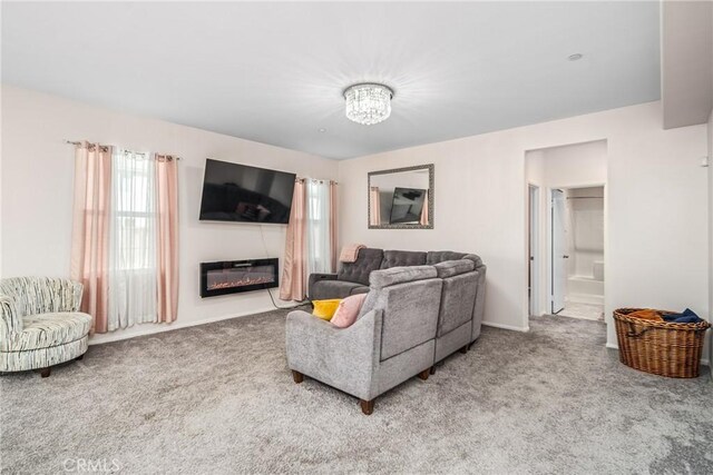 carpeted living room with an inviting chandelier