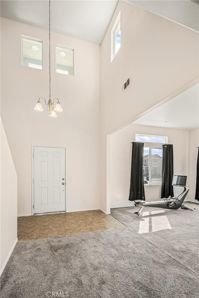 carpeted entrance foyer featuring a chandelier, a towering ceiling, and a wealth of natural light