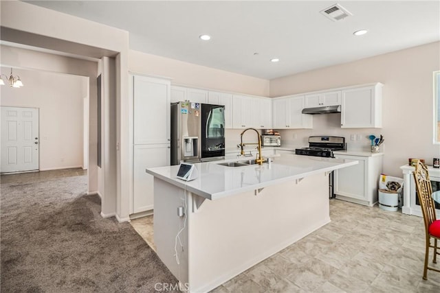 kitchen featuring light carpet, sink, an island with sink, appliances with stainless steel finishes, and white cabinetry