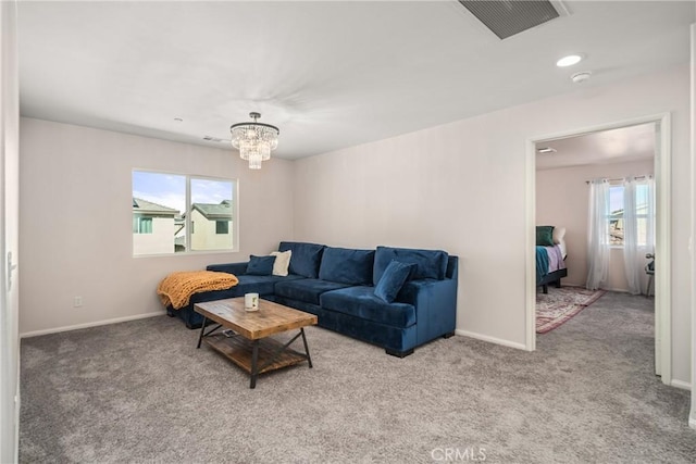 carpeted living room featuring an inviting chandelier