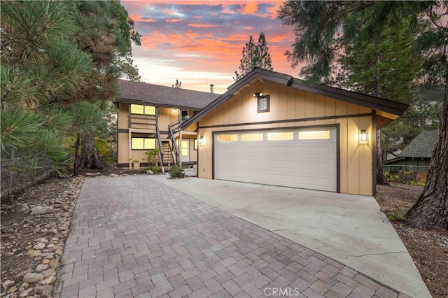 view of front of property with decorative driveway, stairway, and an attached garage