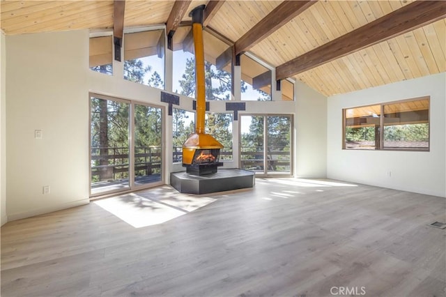 unfurnished living room with hardwood / wood-style flooring, high vaulted ceiling, beamed ceiling, and a wood stove