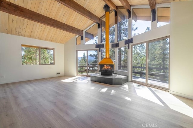 unfurnished living room featuring high vaulted ceiling, beamed ceiling, wood finished floors, and a wood stove