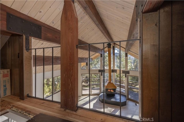 doorway to outside with a wood stove, wooden ceiling, beamed ceiling, high vaulted ceiling, and wood walls