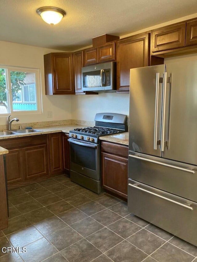 kitchen with dark tile patterned flooring, appliances with stainless steel finishes, and sink