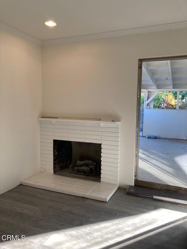 interior details featuring ornamental molding, wood-type flooring, and a brick fireplace