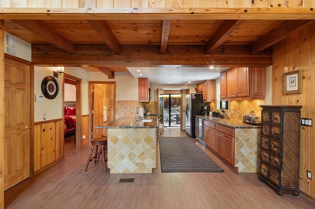 kitchen with sink, a breakfast bar area, kitchen peninsula, and beamed ceiling