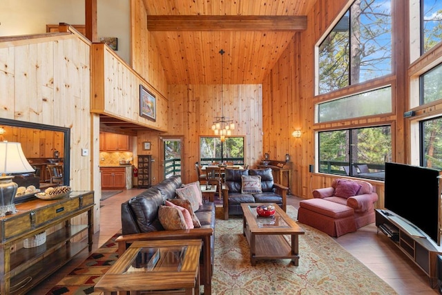 living room with wood-type flooring, beam ceiling, a chandelier, and a high ceiling