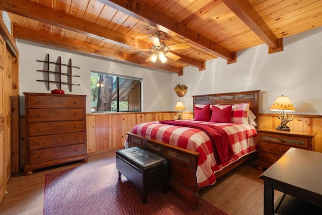 bedroom featuring beamed ceiling, ceiling fan, hardwood / wood-style floors, and wooden walls