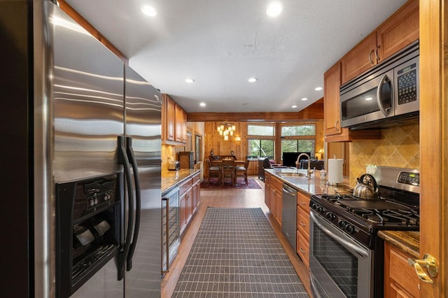 kitchen featuring light stone counters, stainless steel appliances, sink, and wine cooler