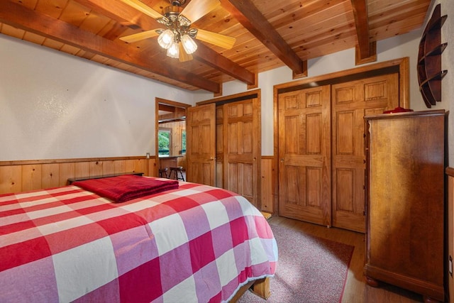 bedroom featuring wooden walls, wood-type flooring, ceiling fan, wood ceiling, and beam ceiling