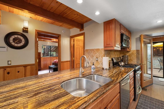 kitchen featuring sink, wood ceiling, dark stone countertops, stainless steel appliances, and beamed ceiling