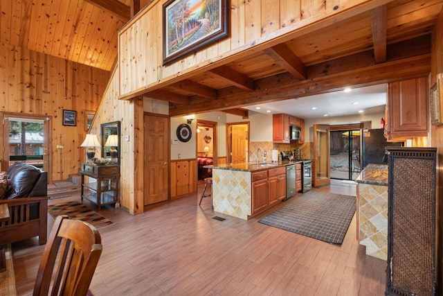 kitchen with sink, a breakfast bar, stone countertops, kitchen peninsula, and beamed ceiling