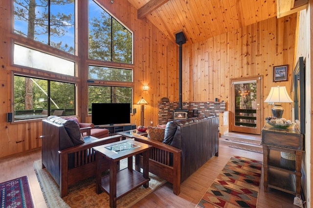 living room with wood ceiling, beam ceiling, high vaulted ceiling, and a wood stove