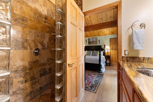 bathroom with wood ceiling, a tile shower, vanity, beam ceiling, and hardwood / wood-style floors