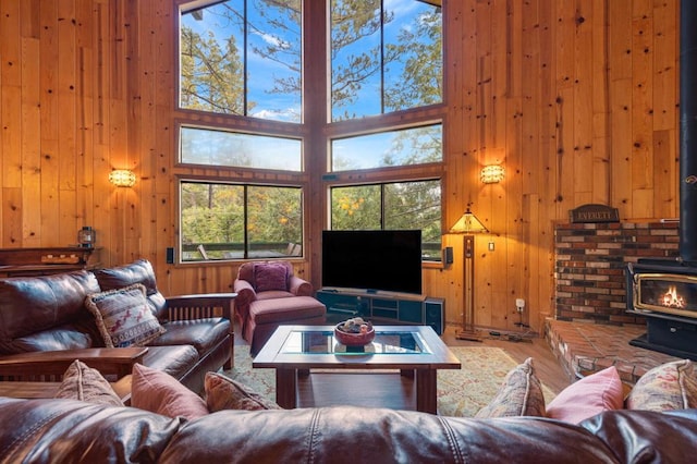 living room with wood walls, hardwood / wood-style floors, a high ceiling, and a wood stove