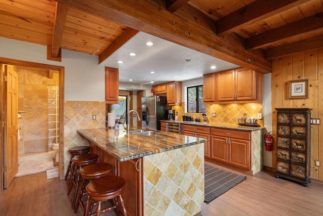 kitchen featuring stainless steel fridge with ice dispenser, wooden ceiling, a kitchen breakfast bar, kitchen peninsula, and light stone countertops