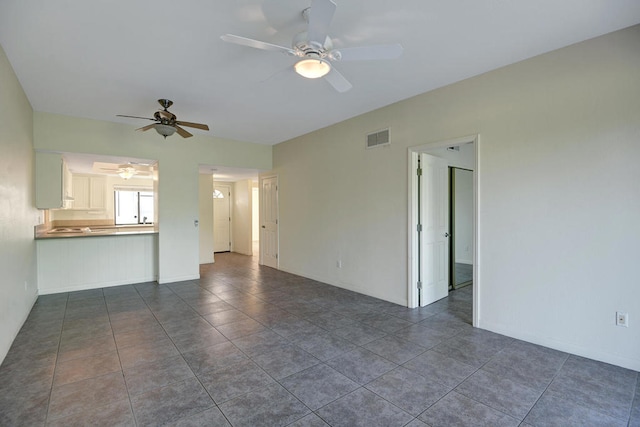 unfurnished living room featuring dark tile patterned floors and ceiling fan