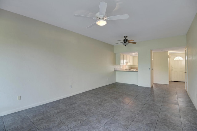 unfurnished living room with dark tile patterned flooring and ceiling fan