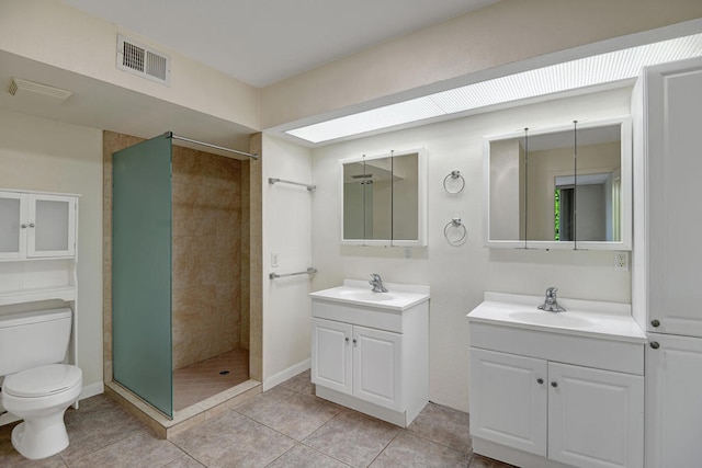 bathroom featuring toilet, vanity, tile patterned floors, and tiled shower