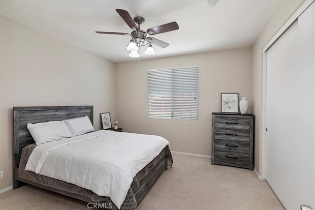 bedroom featuring a closet, light carpet, ceiling fan, and baseboards