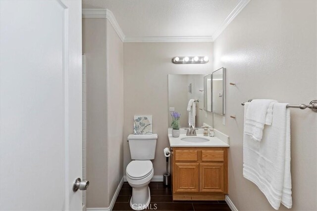 bathroom featuring baseboards, toilet, crown molding, vanity, and wood finish floors