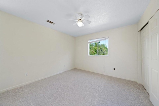 unfurnished bedroom with ceiling fan, light carpet, and a closet