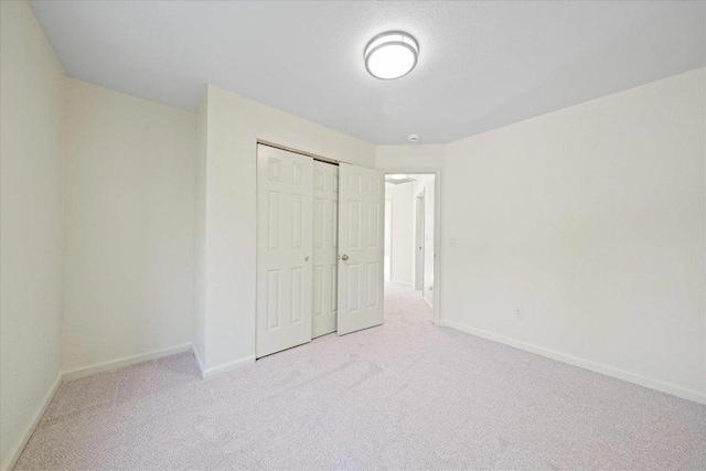 unfurnished bedroom featuring light colored carpet and a closet